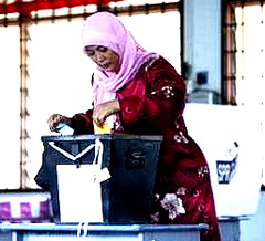 voter placing vote into ballot box 140208