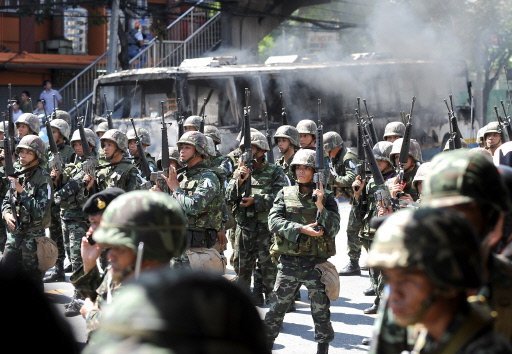 Thai troops battle protesters in Bangkok streets. Burning buses.