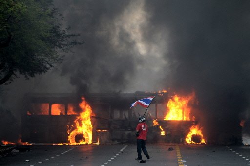 Thai troops battle protesters in Bangkok streets. Burning buses.