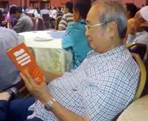 anwar ceramah penang 120611 man reading buku jingga.jpg