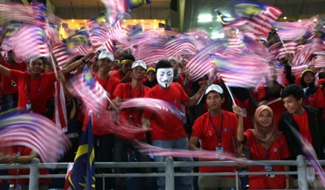 Malaysians wave national flags at a rally to celebrate Malaysia's 55th independence day in Bukit Jalil Stadium